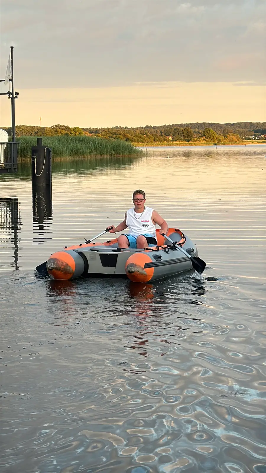 Luca rudert bei Sonnenuntergang ein Schlauchboot über ruhiges Wasser